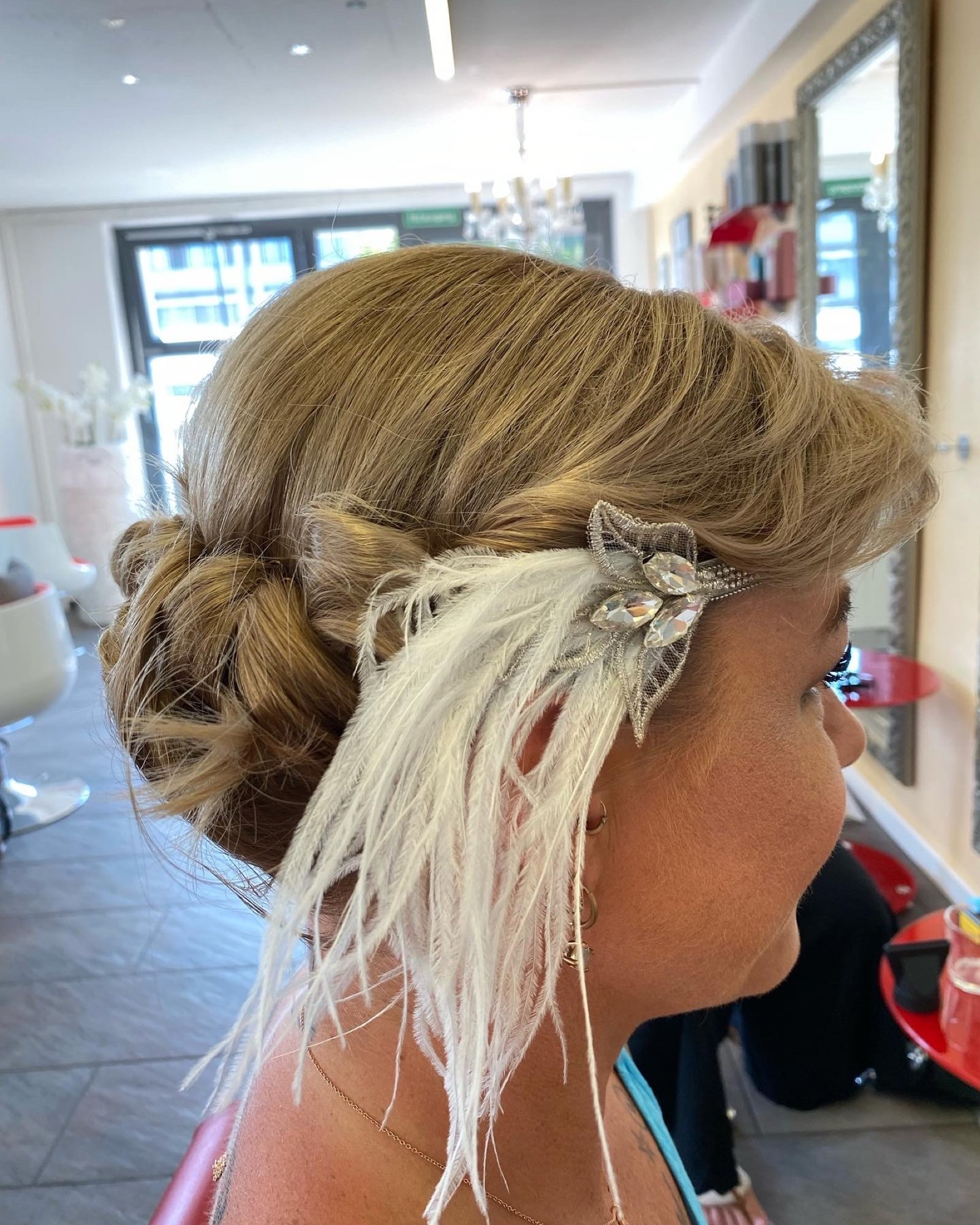 Seitliche Hochsteckfrisur mit Locken und Federschmuck